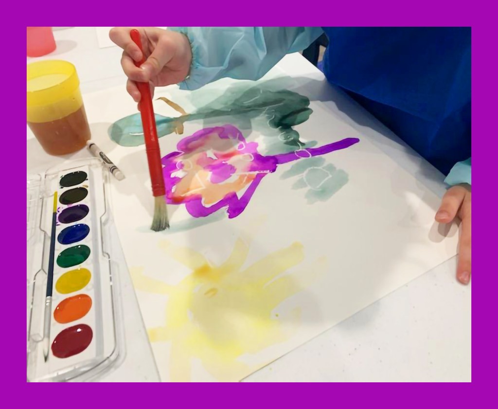 preschool child painting watercolor in art class
